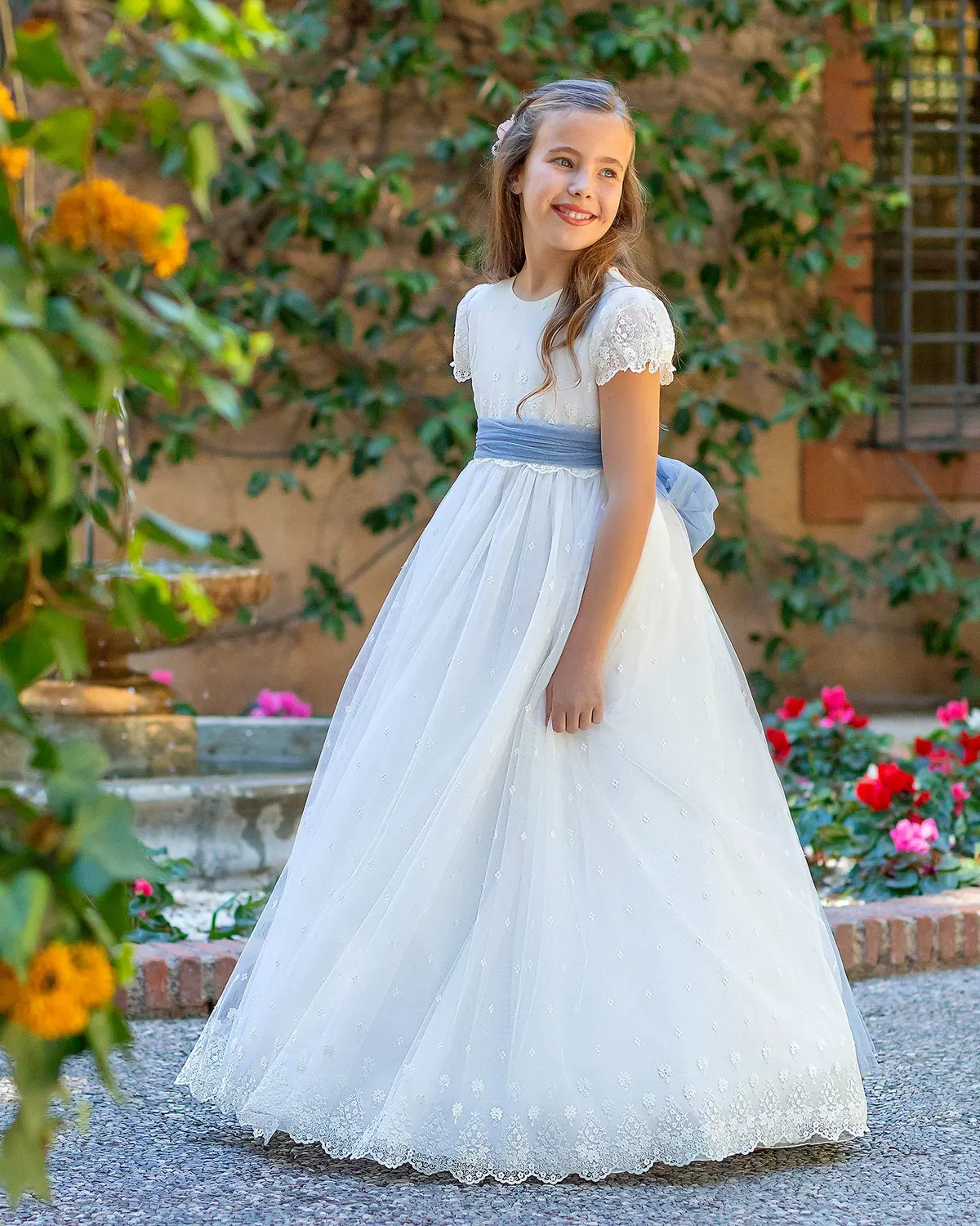 Vestido de comunión Aire Barcelona A780 de frente: manga de encaje, fajín azul empolvado y falda de tul con florecitas