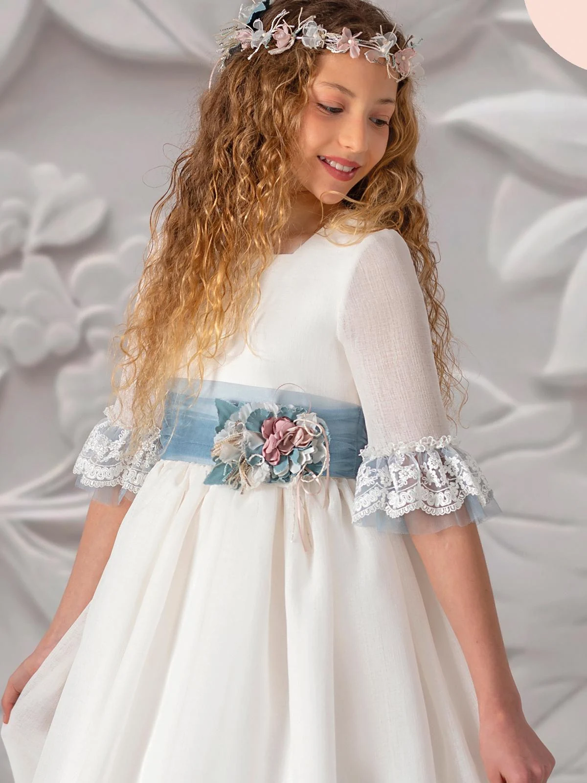 Detalle frontal del Carmy 5804: fajín de tul azul con flores de tela y mangas con volante de encaje