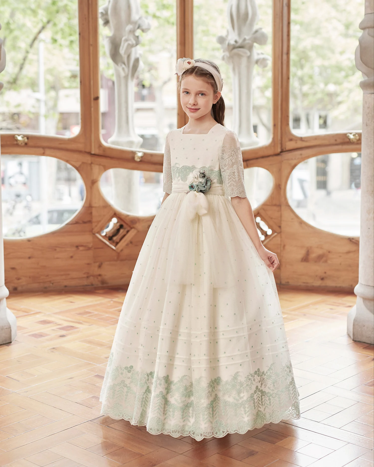 Vestido de comunión Rosa Clará First R423 de frente: topos verde agua, broche de flores y bajo bordado