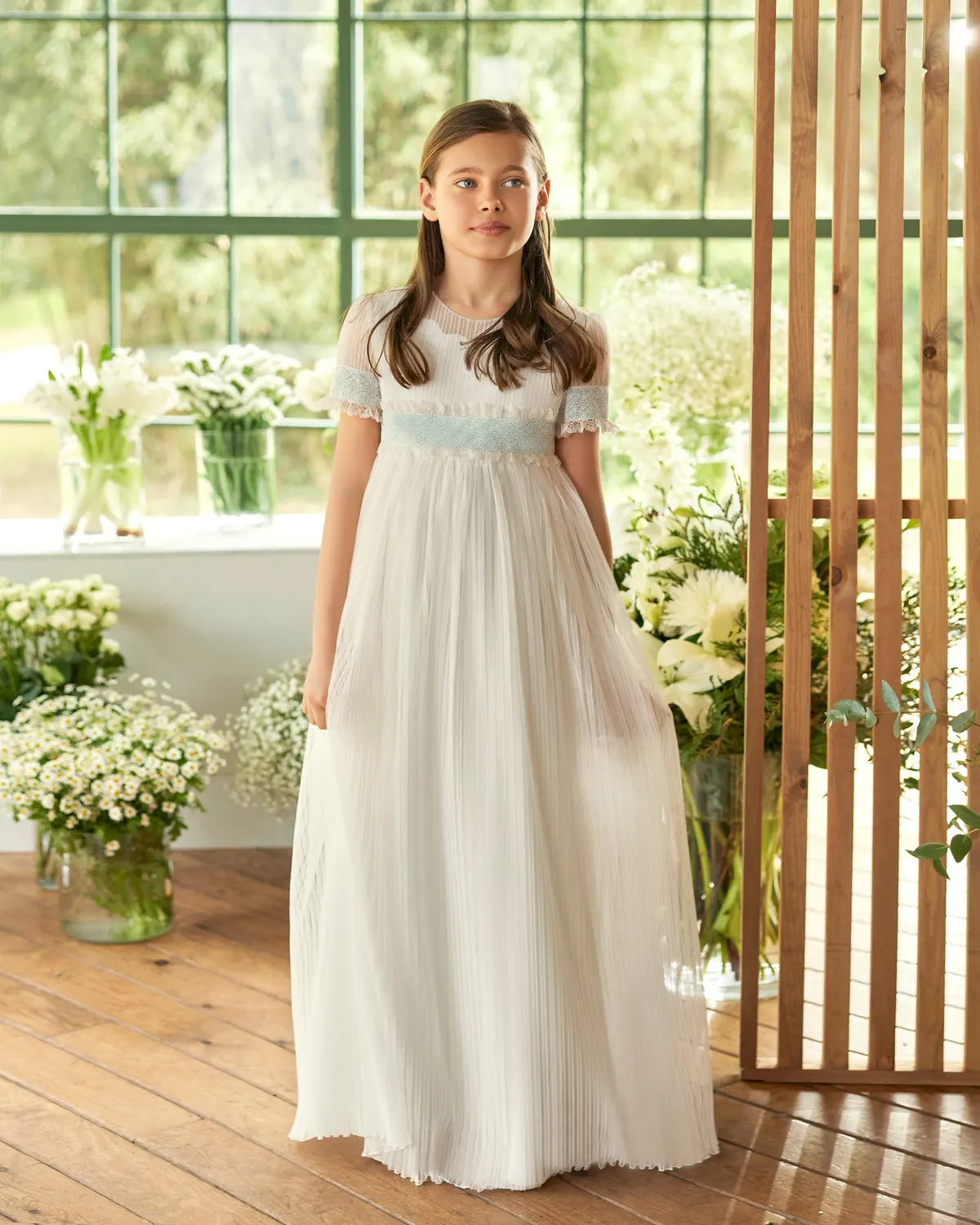 Vestido de comunión Rosa Clará First R603 de frente: tul plisado, talle imperio y fajín de encaje azul celeste