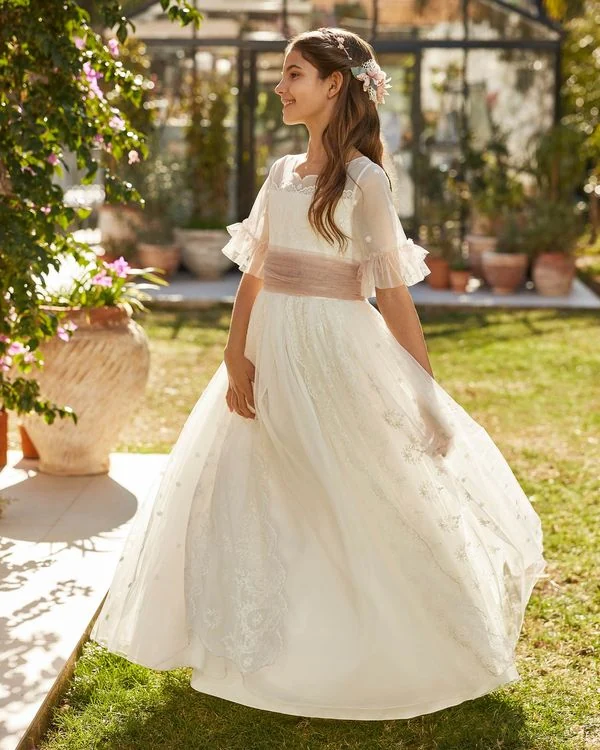 Vestido de comunión Rosa Clará First R709 de perfil: falda de tul con flores bordadas y fajín rosa empolvado
